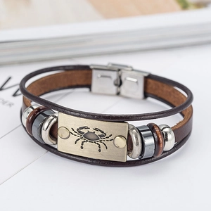 Detail of multi-layer brown leather bracelet with vintage bronze Cancer zodiac sign plate