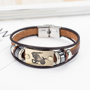 Detailed macro view of woven brown leather bracelet with bronze Capricorn zodiac charm