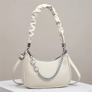 Close-up of cream pleated crescent bag with silver chain and ruffled top handle detail