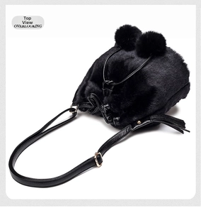 Overlooking view of a black faux fur bucket bag with plush pom-poms and leather strap