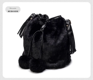 Detail of black faux fur bucket bag featuring plush pom-poms and drawstring tassels