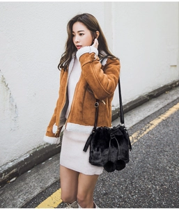 Detail of a black plush faux fur bucket bag with a drawstring and cute pompom charms