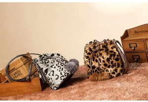 Detail view of two faux fur leopard print bucket bags with drawstring and soft pom-poms