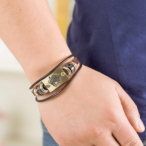 Close-up of multilayer brown leather bracelet with brass bull charm and metallic beads