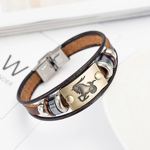 Macro detail of brown braided leather bracelet with brass Capricorn zodiac plate and steel clasp