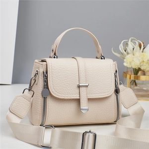 Close-up of beige lychee textured handbag with wide fabric strap and silver hardware