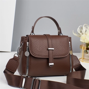 Detail of a brown lychee pattern leather crossbody bag with silver hardware and wide strap
