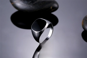 Detailed view of a silver men's signet ring with a polished black enamel square top inlay