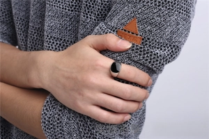 Detailed close-up of a men's classic silver-toned signet ring with black oil drip on finger.