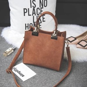 Detail of a brown frosted small square bag with gold hardware on a plush white mat