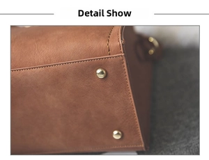 Detail view of the brown leather bag bottom with protective gold metal feet and stitching
