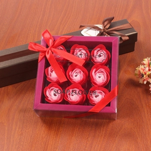 Detailed view of 9 gradient pink soap rose flowers in a gift box with a red ribbon