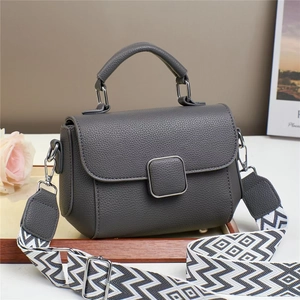 Deep grey litchi leather crossbody bag with wide geometric strap on a white surface