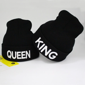 Detail shot of 3D embroidered KING and QUEEN lettering on black ribbed knit beanies