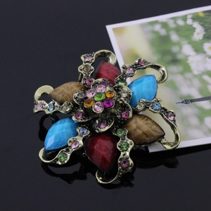Close-up of vintage flower brooch with colorful resin gemstones and bronze metal detailing