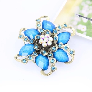 Macro detail of vintage bronze flower brooch with blue gems and rainbow rhinestones