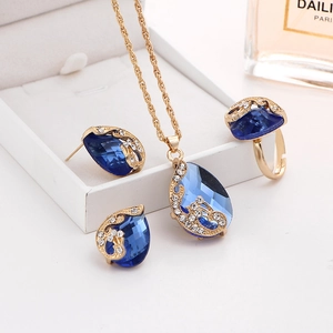 Detail view of gold-plated peacock jewelry set with blue crystals on elegant white decor