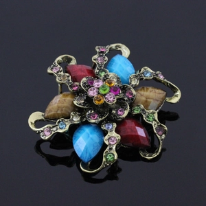 Detailed close-up of retro flower brooch with colorful resin gems on black reflective surface