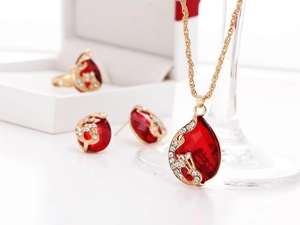 Detail of red teardrop crystal jewelry set including necklace, earrings and ring on white base
