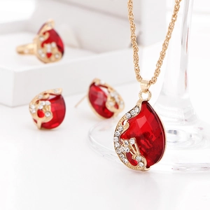 Close-up of gold-plated jewelry set with red teardrop crystals and sparkling studs