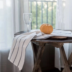Close-up of white cotton napkin with blue stripes on a wooden table in sunlight