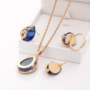 Detailed macro view of gold-plated peacock set with blue drop crystal and white rhinestones