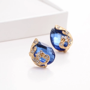 Detail of dark blue teardrop crystal earrings with gold finish and white rhinestones