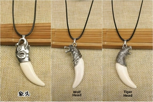Detail of faux bone pendants with silver wolf, tiger, and elephant metal carvings on black cord