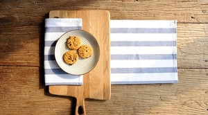 Flat lay of blue and white striped cotton table cloth with wooden board on rustic wood