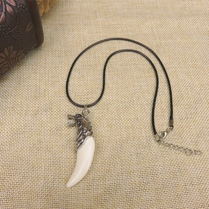 Close-up of wolf tooth resin pendant with silver wolf head on rustic linen background