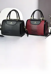Detail von Boston-Taschen aus geprägtem Krokodilleder in Schwarz und Weinrot mit Gold-Hardware