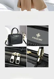 Detailansicht der schwarzen Handtasche mit Krokodilmuster, Logo und Reißverschlüssen