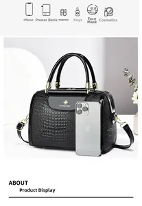Kapazitätsdetail der schwarzen Handtasche mit Krokoprägung im Vergleich zum iPhone-Format