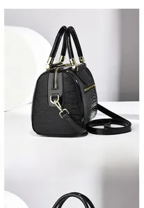 Detail der eleganten schwarzen Handtasche mit Krokodilprägung, Lackbesatz und Goldreißverschluss