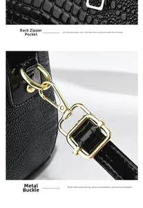 Detail einer schwarzen Kroko-Ledertasche mit goldenen Beschlägen und Reißverschlusstasche