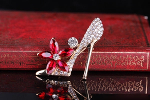 Close-up of crystal high heel brooch with red floral gems on a vintage book
