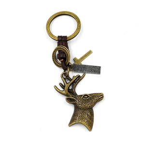 Vintage metal elk head and brown leather woven keychain with engraved pendant on white background