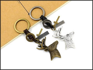 Detailed view of metal elk pendants with engraved tags on braided leather keychains