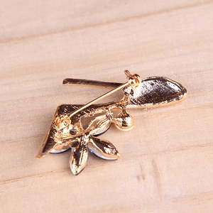 Golden high heel brooch with crystals and flower design on a light wood background
