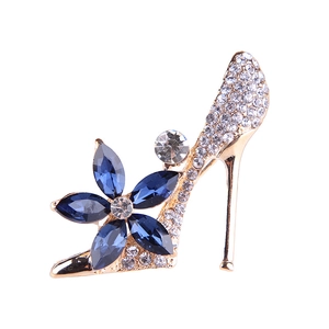 Fashionable golden high heel brooch with dark blue crystals and sparkling white rhinestones
