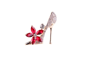 Detailed view of gold high heel brooch with white rhinestones and red crystal flower