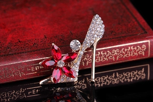 Detail of high heel brooch with red crystal flower and pavé diamonds on vintage book