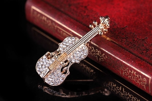 Dettaglio spilla a violino con strass su libro rosso vintage con riflesso su specchio