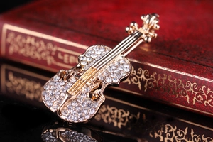 Macro di spilla a violino dorata con strass posata su un libro vintage