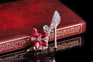 Detailed close-up of high heel brooch with red crystal flower and sparkling rhinestones
