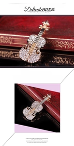 Dettaglio della spilla a forma di violino con finitura dorata e strass luccicanti