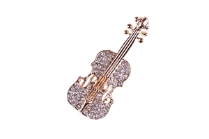 Dettaglio della spilla a forma di violino dorato con strass bianchi e finitura lucida