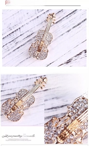 Dettaglio macro della spilla a violino in metallo dorato con strass scintillanti