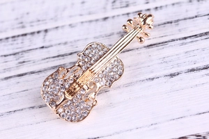 Dettaglio macro di un'elegante spilla a violino dorata con strass brillanti incastonati
