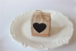 Detail of kraft paper favor box with heart cutout and rustic jute twine on white ceramic plate